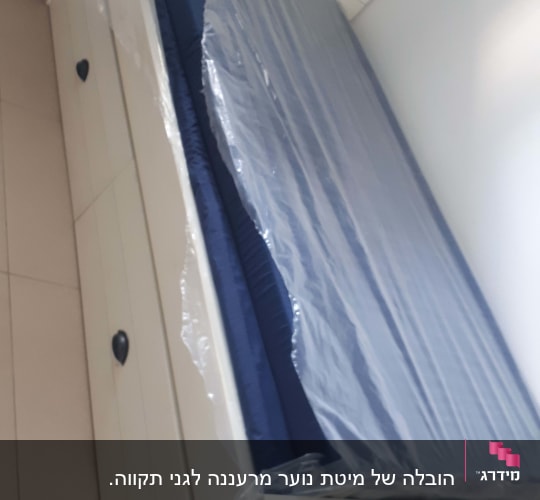 מזרן עטוף בניילון על מיטה לבנה